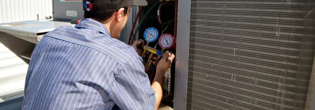 HVAC technician servicing a condenser unit in Iola