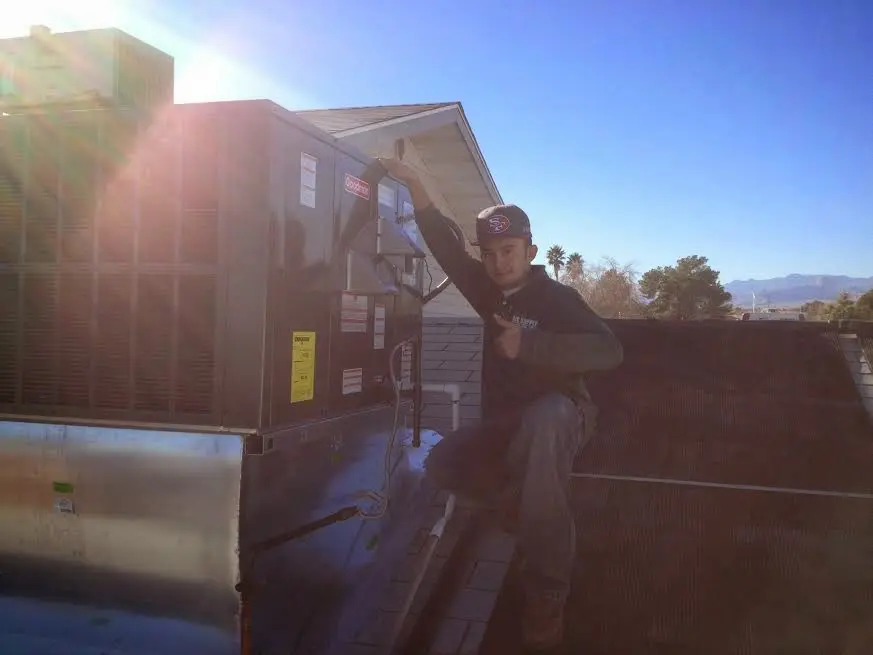 HVAC technician performing AC Tune-Up on a rooftop unit in Iola